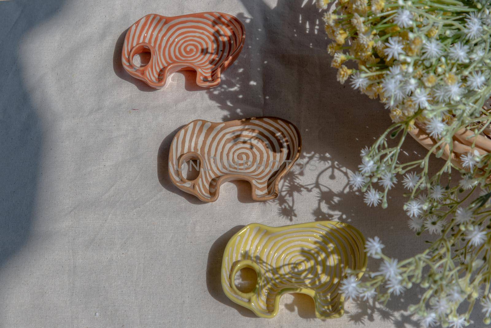 Set of Elephants shaped ceramics cup and bouquet of flowers to Decorate the house beautifully. Elephant shaped cup for dipping sauce, Copy space, Selective focus.