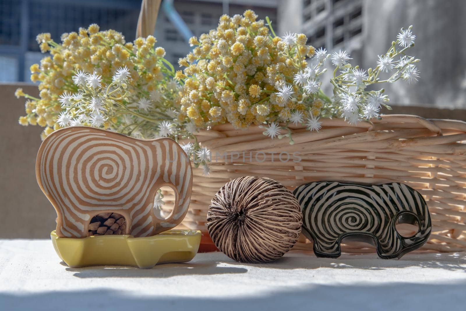 Set of Elephants shaped ceramics cup with Dried cerbera oddloam's seed and Bouquet of flowers in woven basket to Decorate the house beautifully. Elephants shaped cup for dipping sauce, Selective focus.