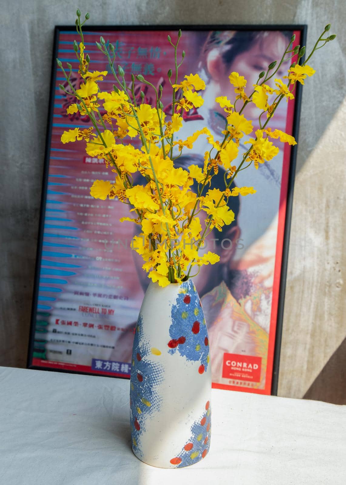 Yellow flowers in Handmade ceramic vase and with Classic chinese poster movie frame with old ruins cement wall. Home decor, Selective focus.