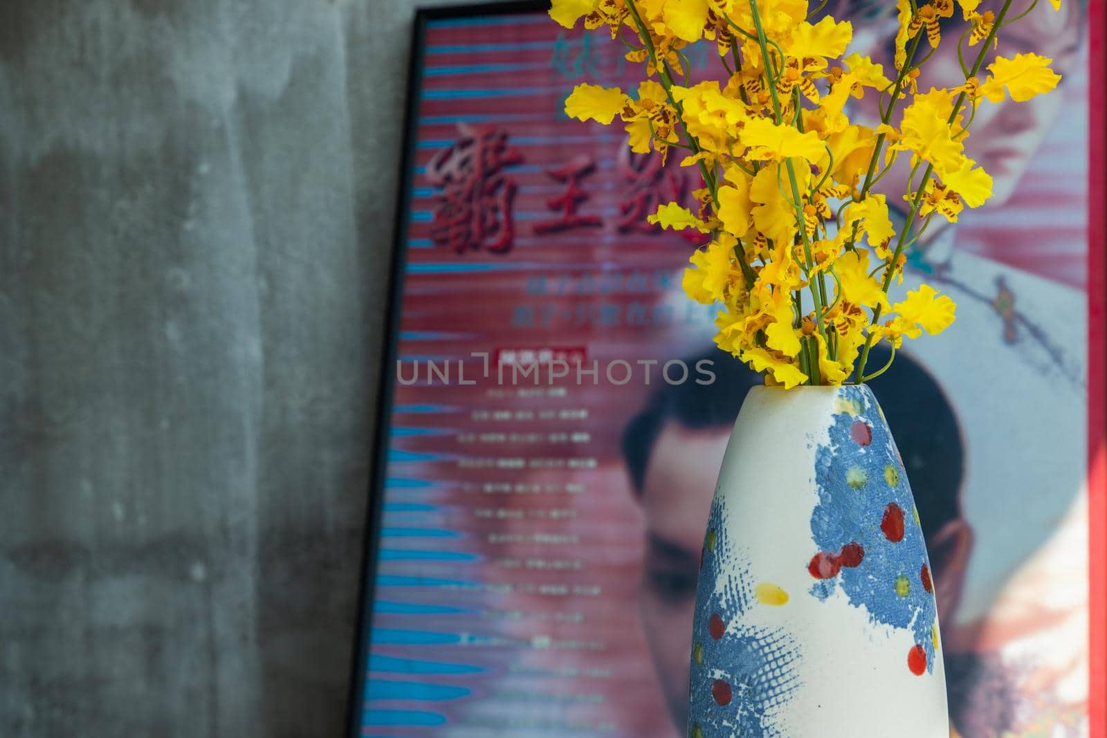 Yellow flowers in Handmade ceramic vase and with Classic chinese poster movie frame with old ruins cement wall. Home decor, Selective focus.