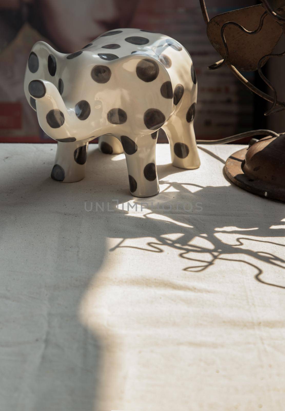 Elephants shaped ceramic and Vintage metal fan on white textured table cloth. Home decor, Copy space, No focus, specifically.