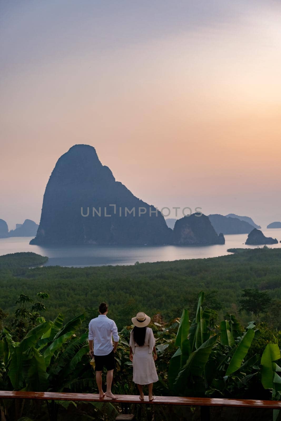 couple men and woman mid age watching sunrise in Phangnga bay Thailand, Phanga bay viewpoint, couple watching sunrise on the edge of a swimming pool, infinity pool look out over Phangnga Bay Thailand by fokkebok