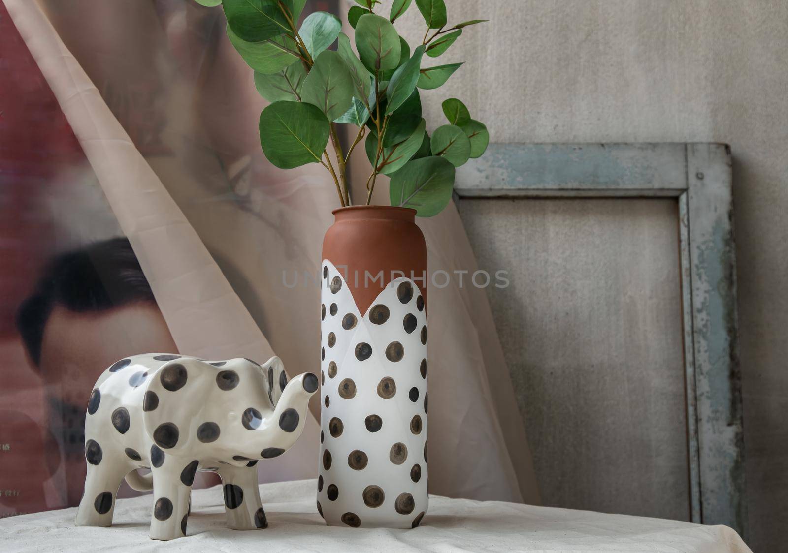 Bangkok, Thailand - Feb 06, 2021 : Elephant shaped ceramic and Handmade Ceramic Polka Dotted Vase on white textured table cloth. Home decor, Space for text, Selective focus.