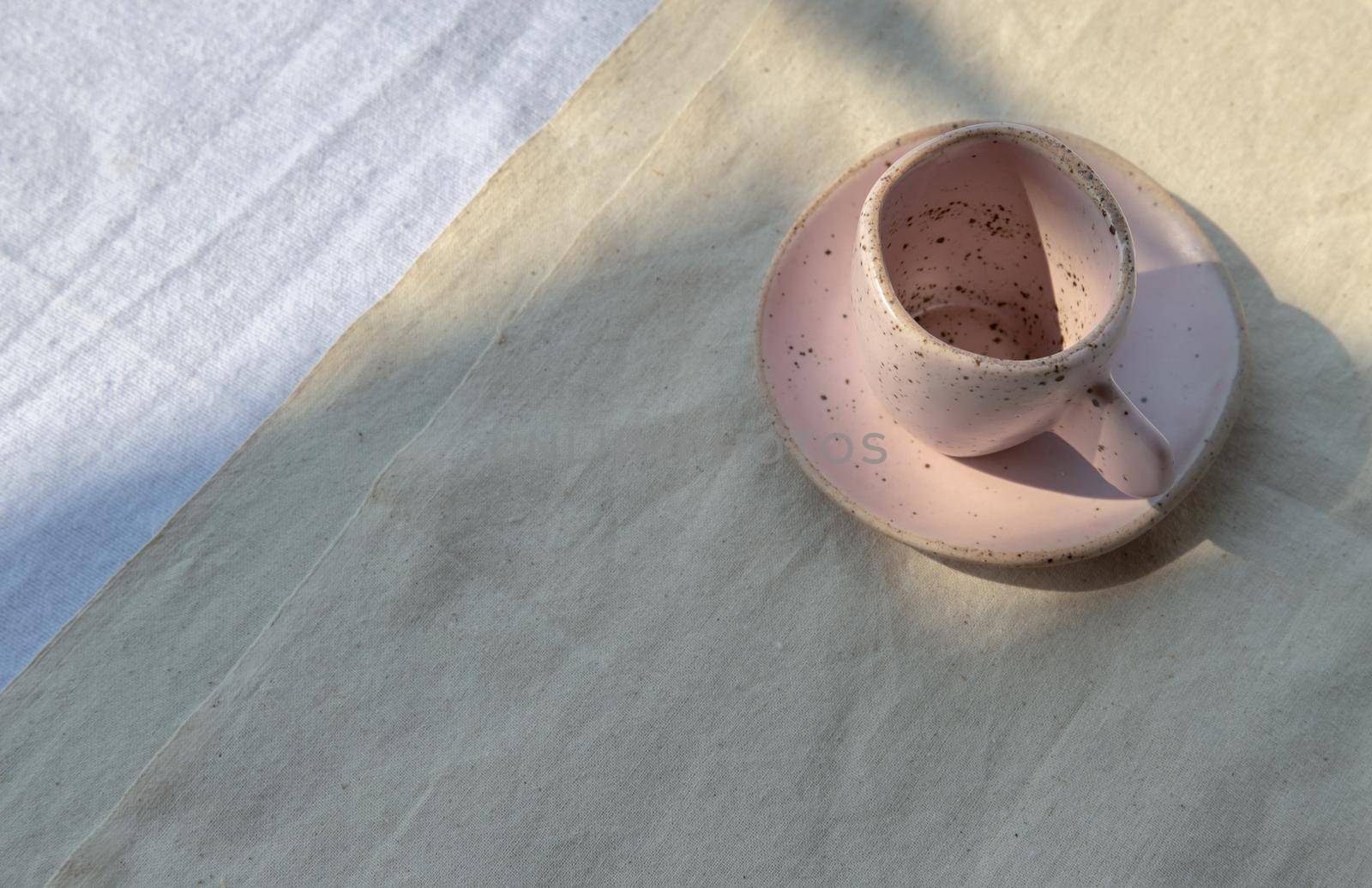 Beautiful pink ceramic mug on white textured table cloth. Space for text, Top view, Selective focus.
