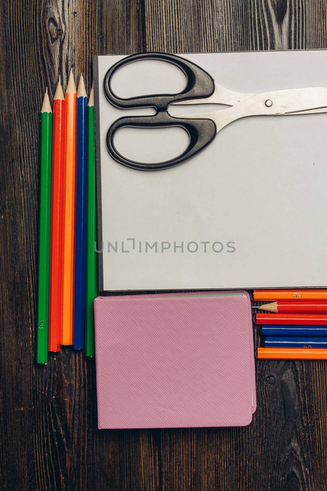 notepads colored pencils and stationery in a glass on a wooden table top view. High quality photo