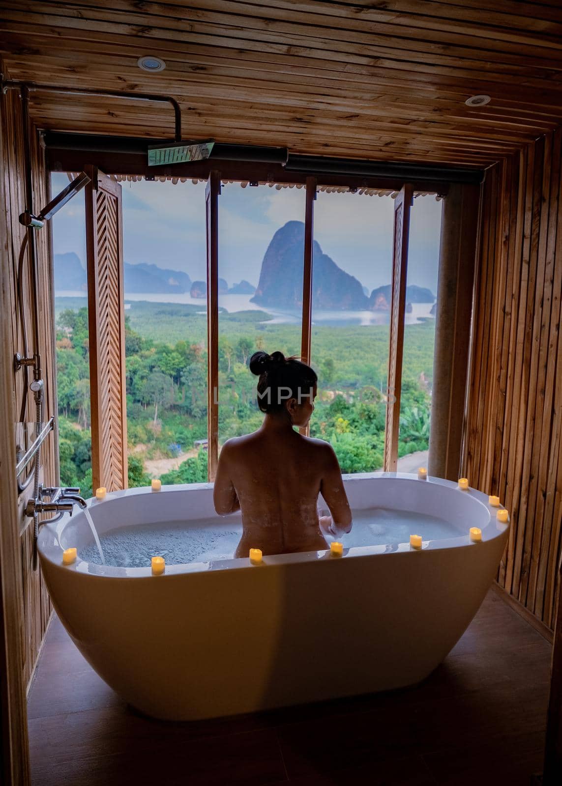 woman in bath tub looking out window of bathroom, asian woman mid age,Romantic moments in the bathroom on vacation at Phangga Thailand by fokkebok