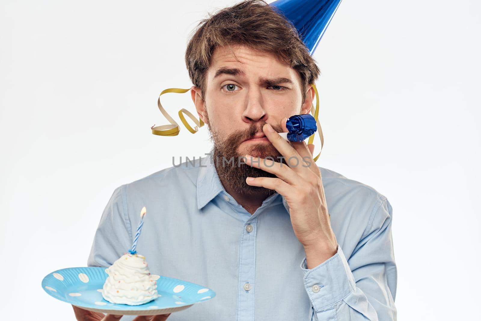 A man with a cake plate and in a blue shirt on a light background birthday party corporate cap. High quality photo