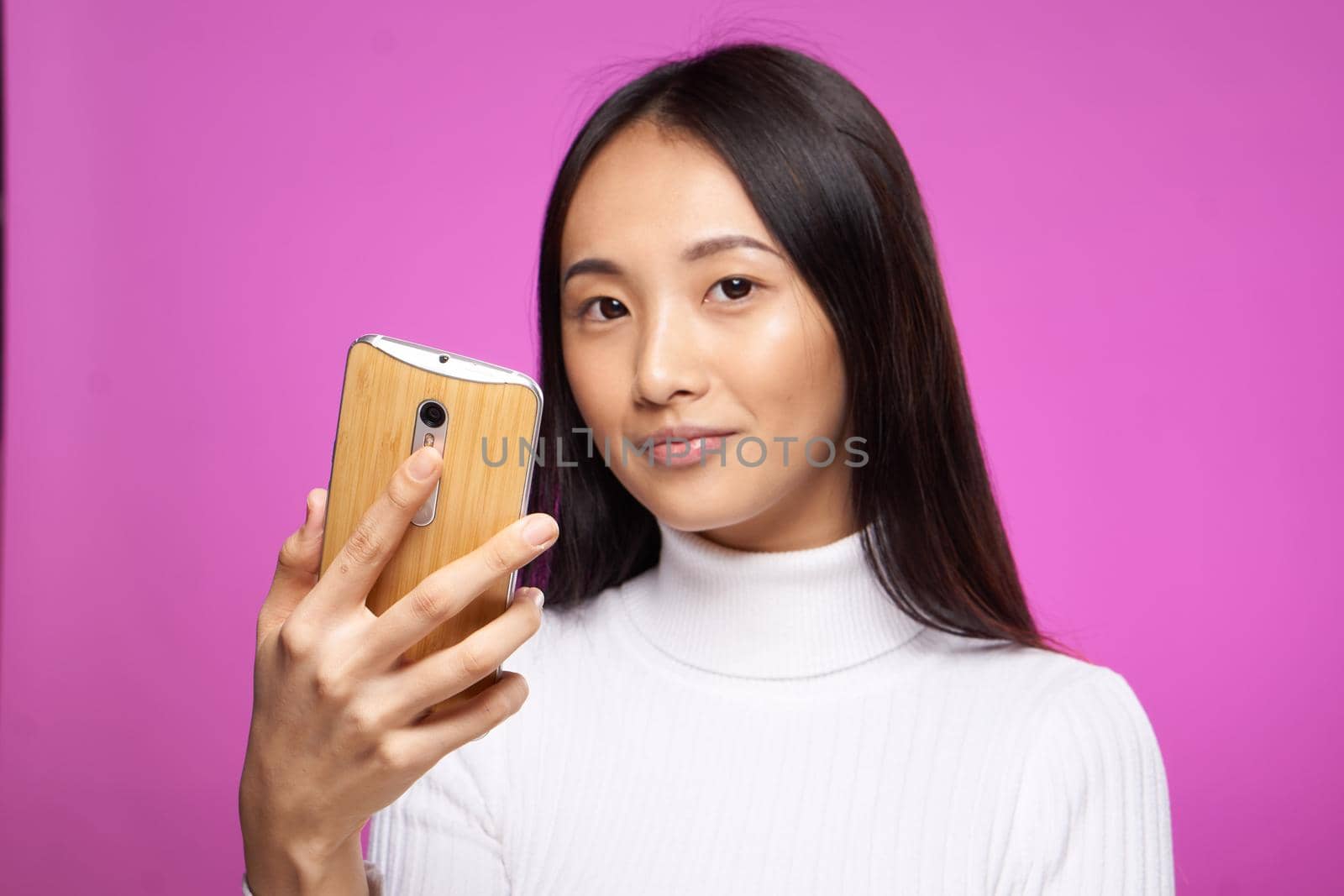cute asian appearance phone in hand internet communication technology pink background. High quality photo