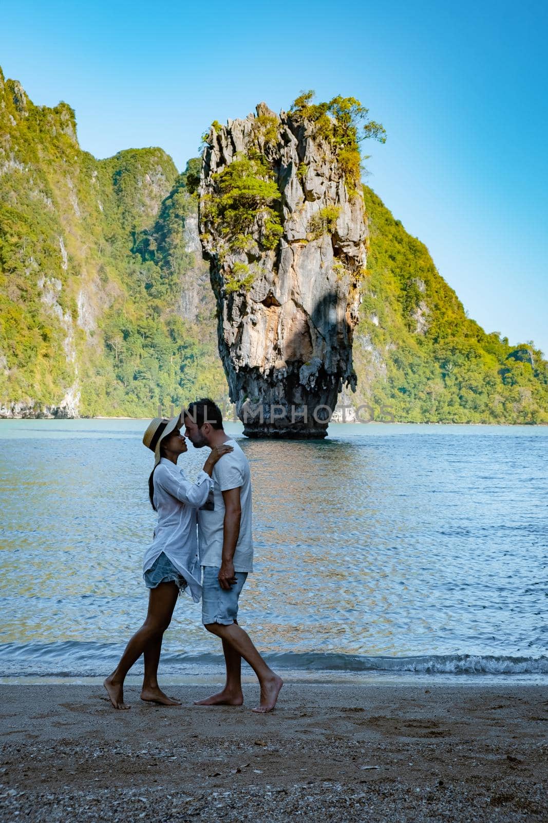 James Bond island near Phuket in Thailand. Famous landmark and famous travel destination, couple men and woman mid age visiting James Bond island in Krabi Thailand. European man and Asian woman on vacation