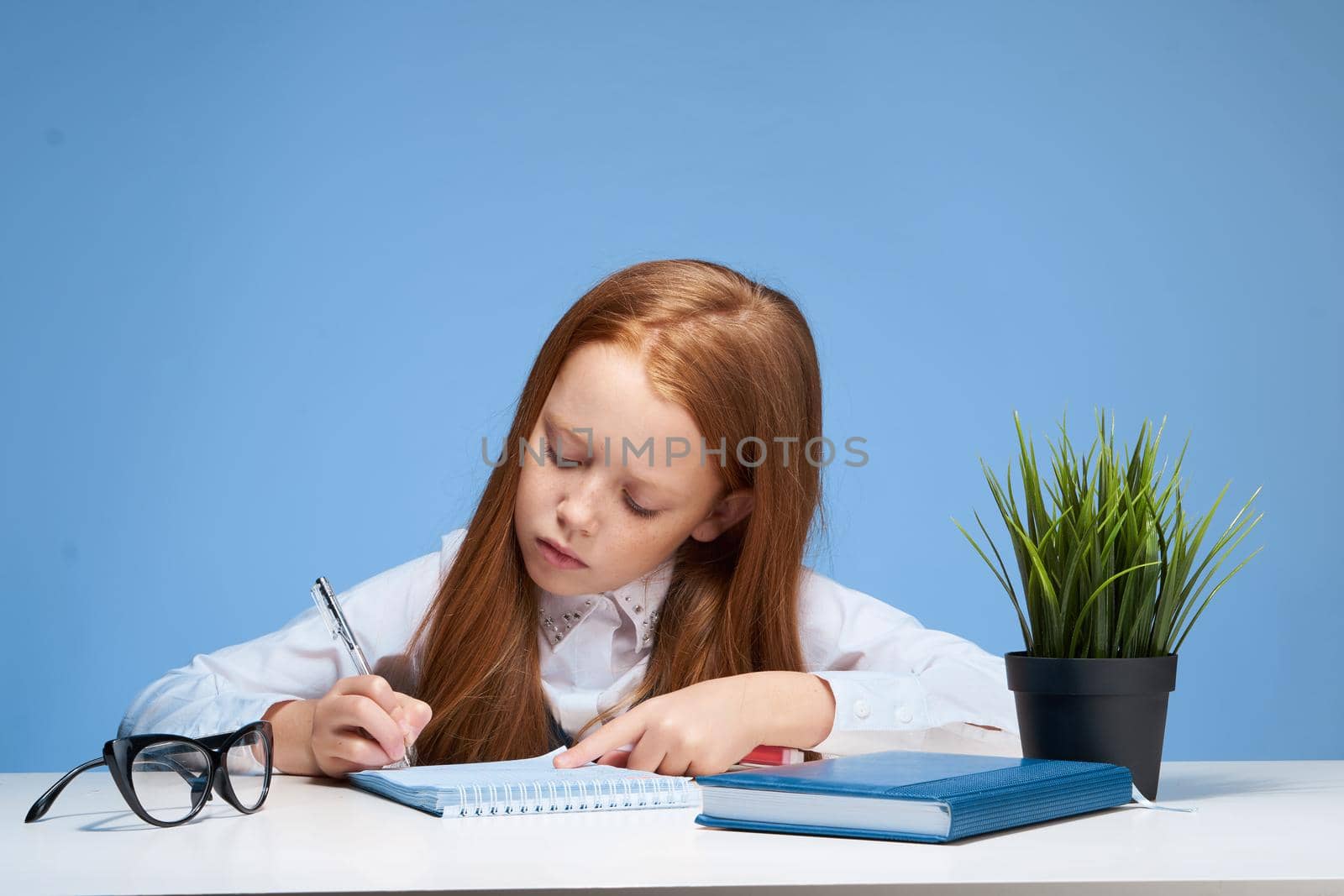 red-haired girl doing homework at the table school subject education. High quality photo