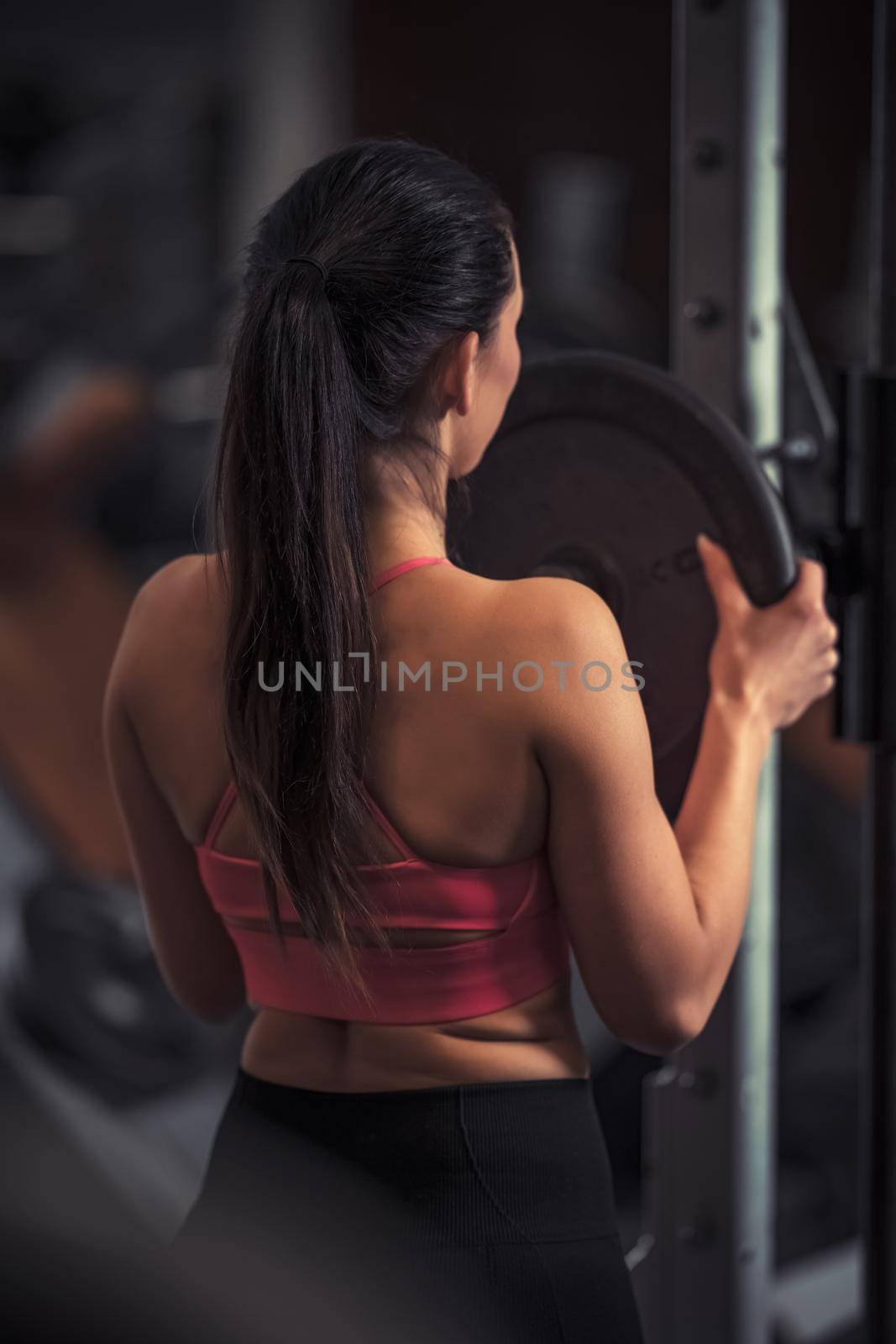 pretty young fitness woman at the gym on a fitness machine by Edophoto