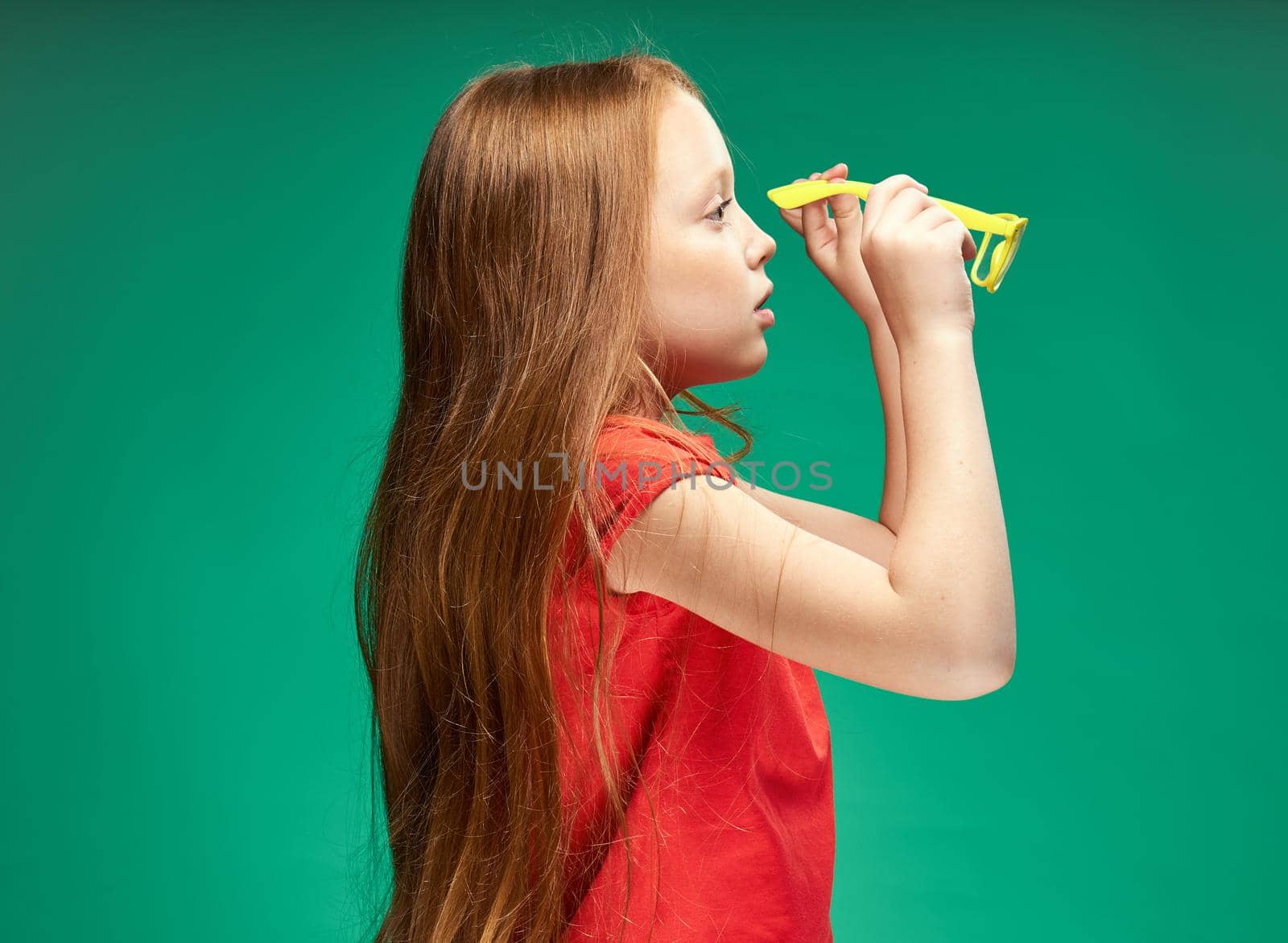 cheerful girl with red hair and a red t-shirt yellow glasses emotions studio. High quality photo