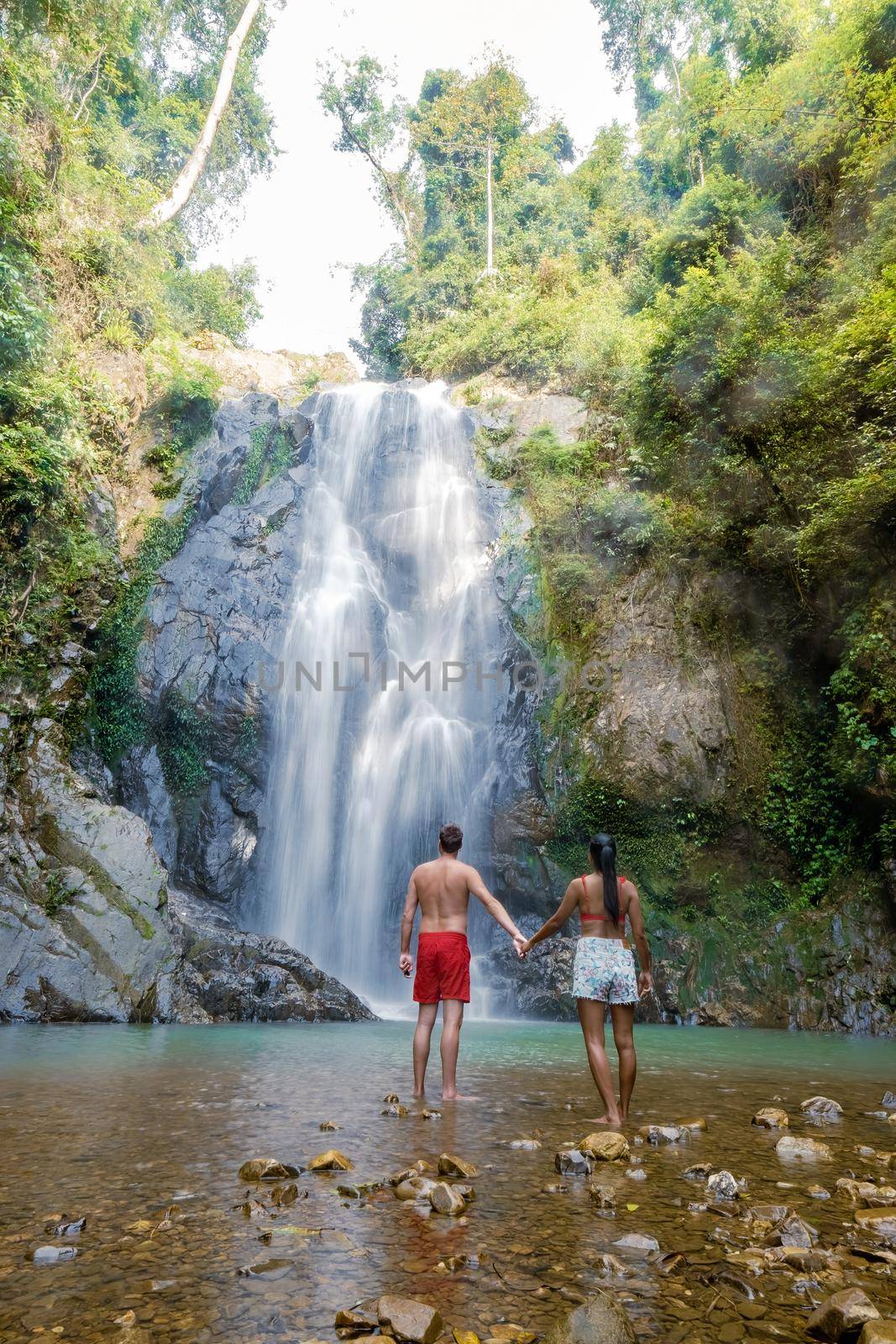 couple of men and women mid-age visiting a waterfall in Thailand, A tourist is enjoying the beauty of the waterfall in Chumphon province, Thailand, Klongphrao waterfall Thailand. Asia