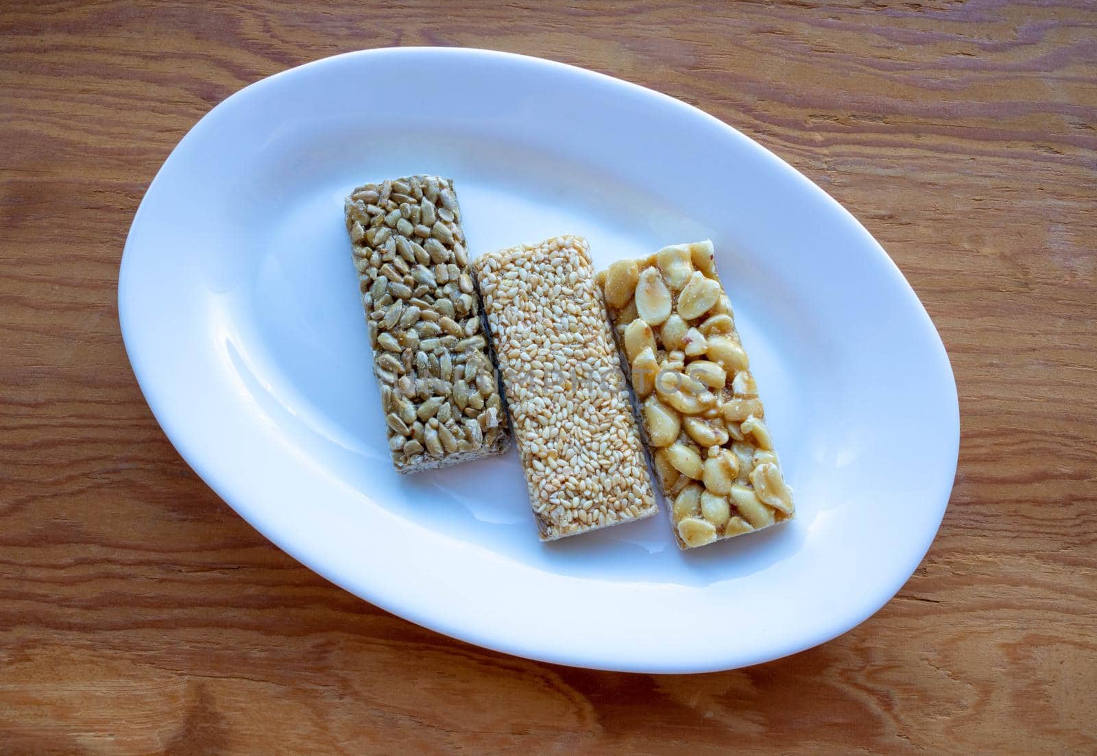 Delicious honey kozinaki on a white plate on a wooden table.