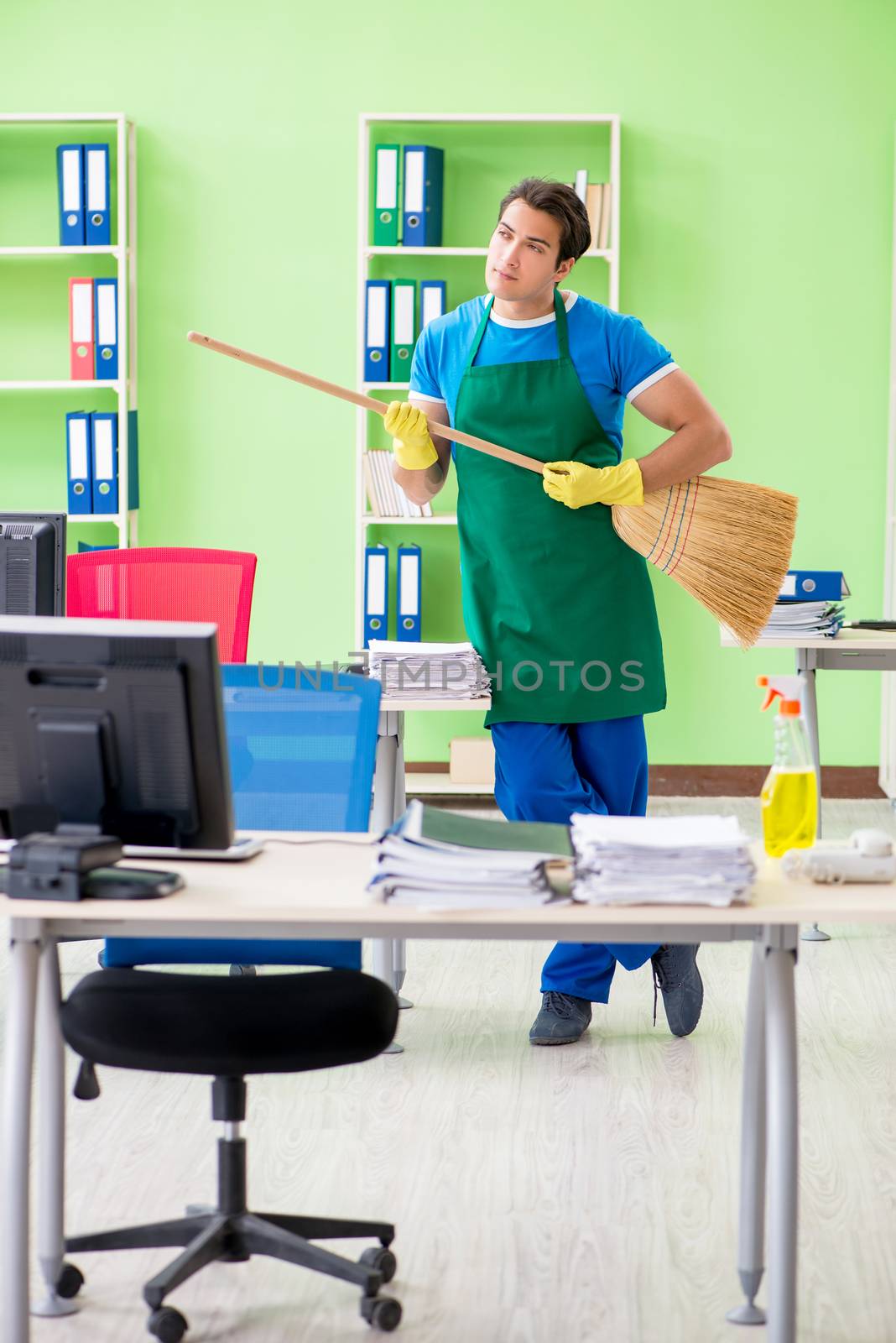 Young male handsome professional cleaner cleaning floor with broom