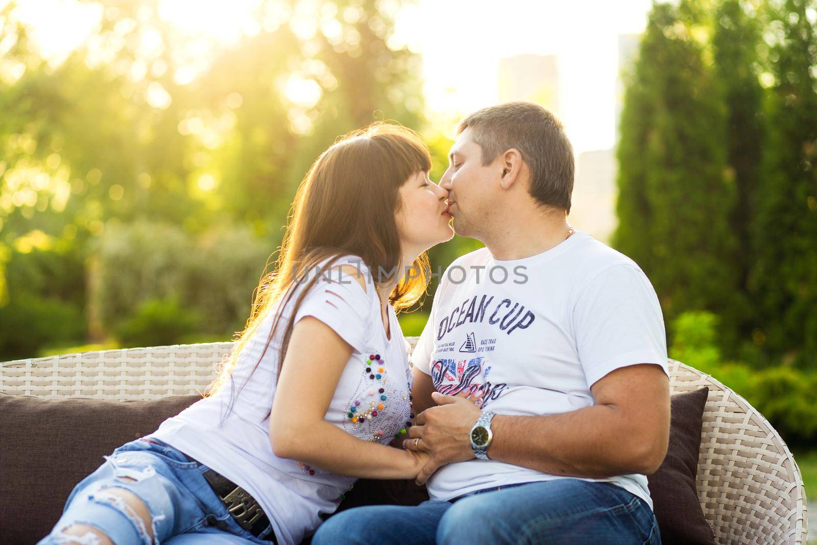 Young romantic couple have fun enjoy each other on the bench in green summer park.