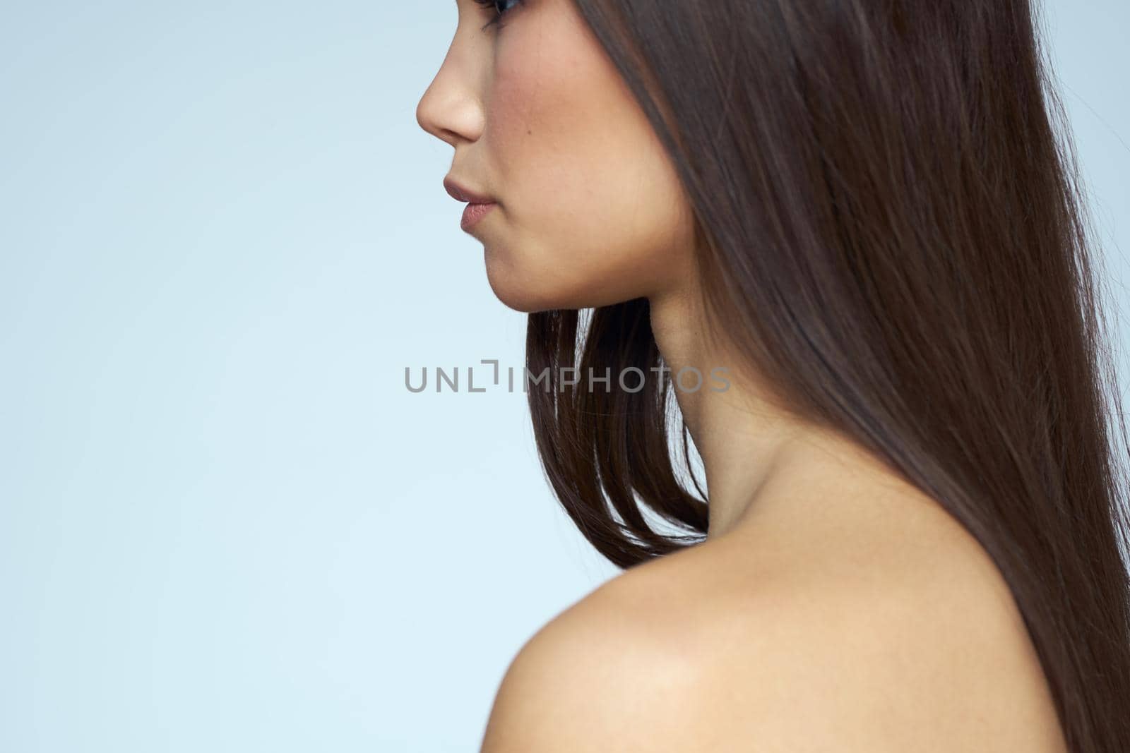 Woman with naked shoulders long hair clean skin cropped view blue background. High quality photo