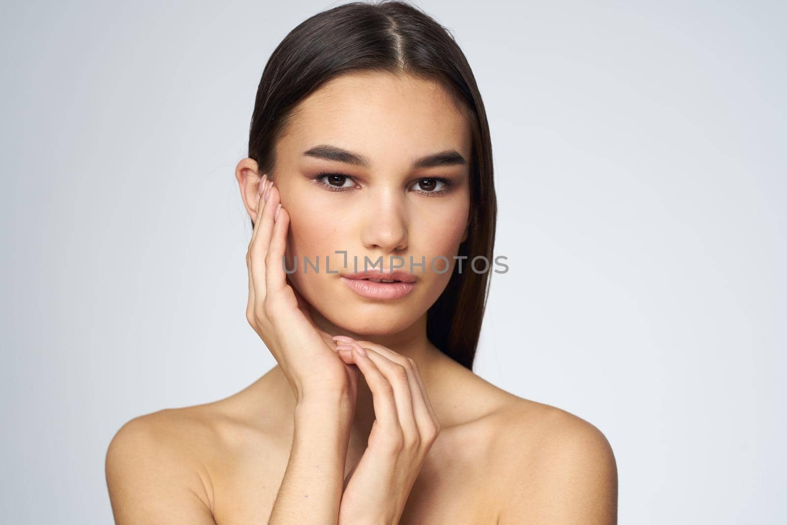 Woman with long hair bared shoulders clean skin body care light background. High quality photo