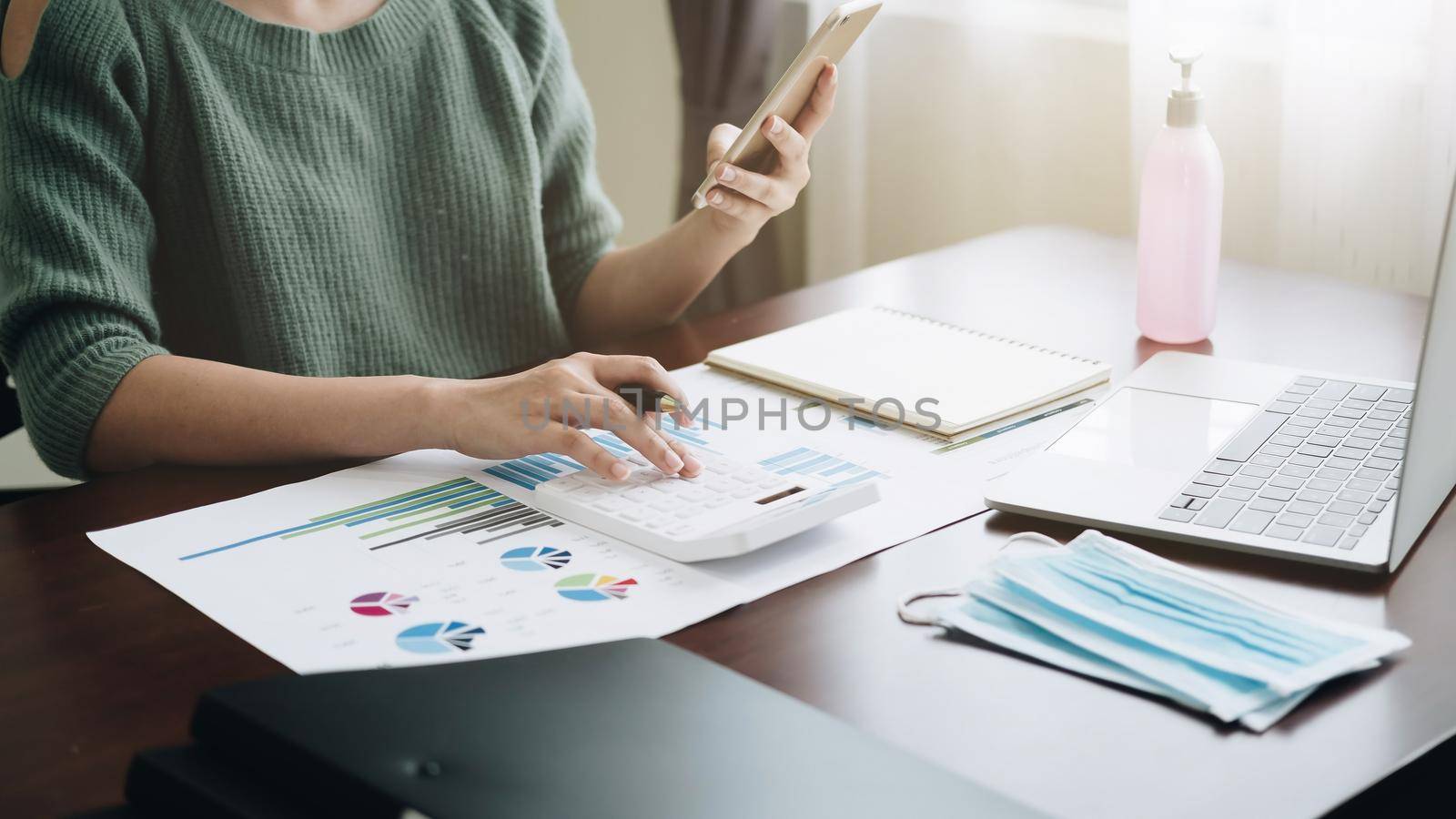 accounting, taxes and finances concept - woman with smartphone and calculator wearing face protective medical mask for protection from virus disease at home