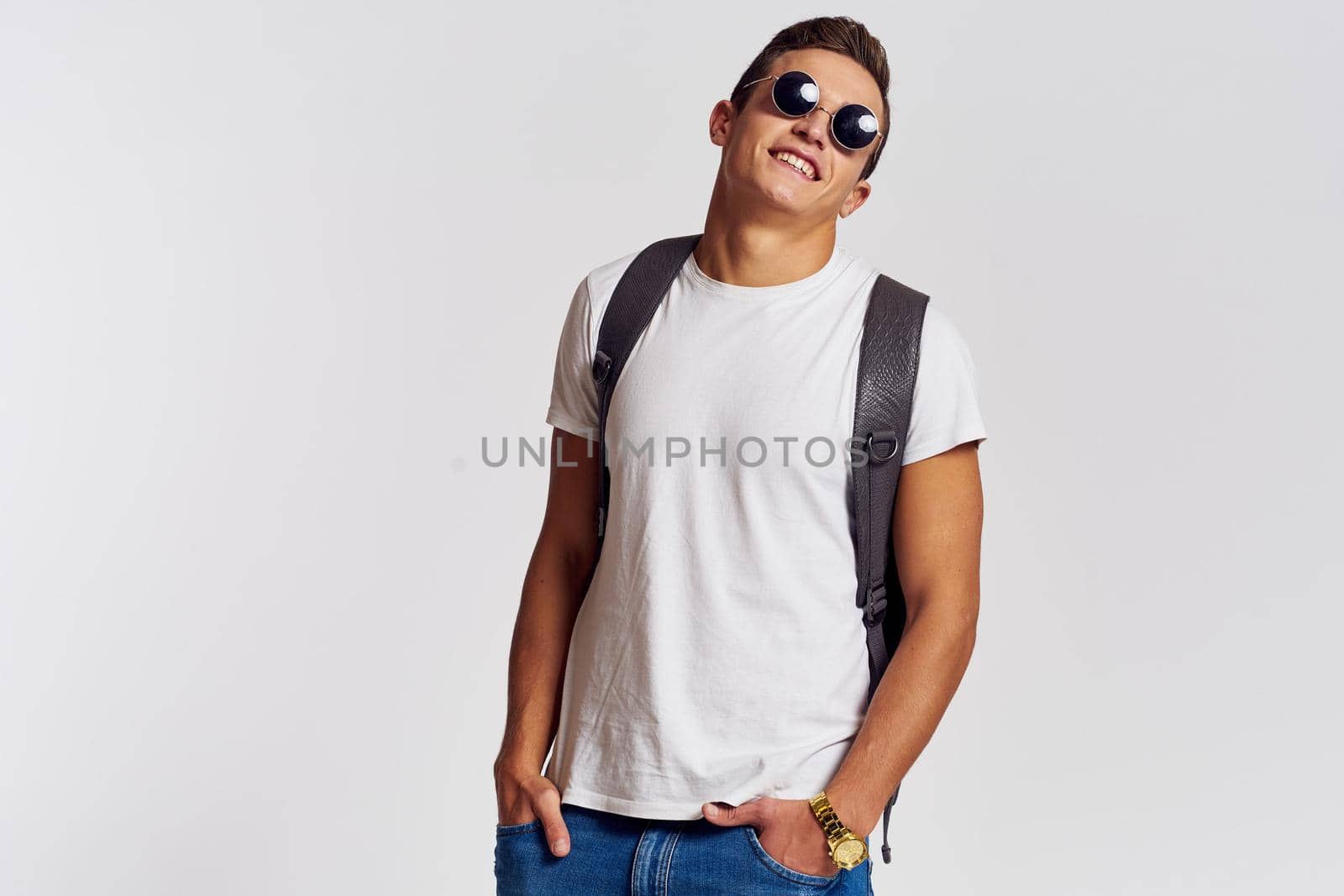 man in sunglasses with a backpack on his back and in a white t-shirt on a light background cropped view of emotion. High quality photo