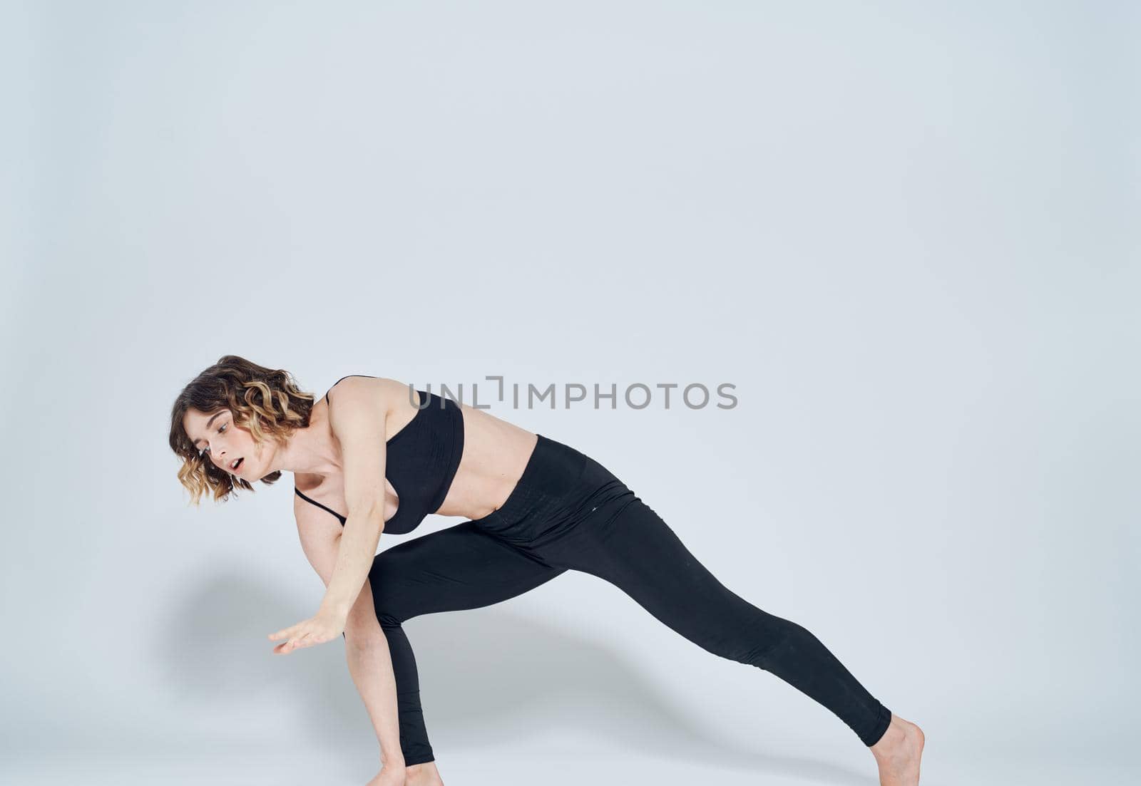 A slender woman in sportswear is engaged in fitness on a light background. High quality photo