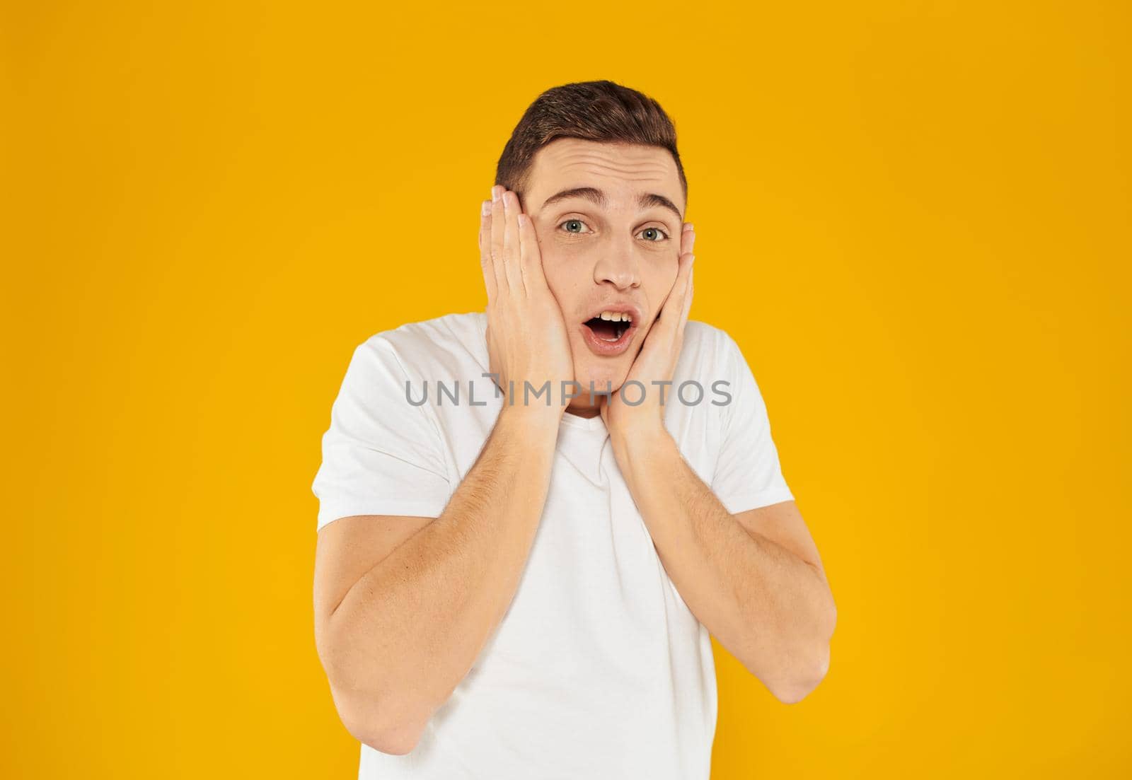 Angry guy gesturing with his hands on a yellow background cropped view. High quality photo