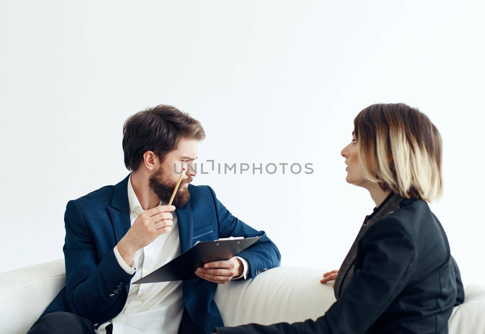 Business man and woman employees communicating on the couch indoors by SHOTPRIME