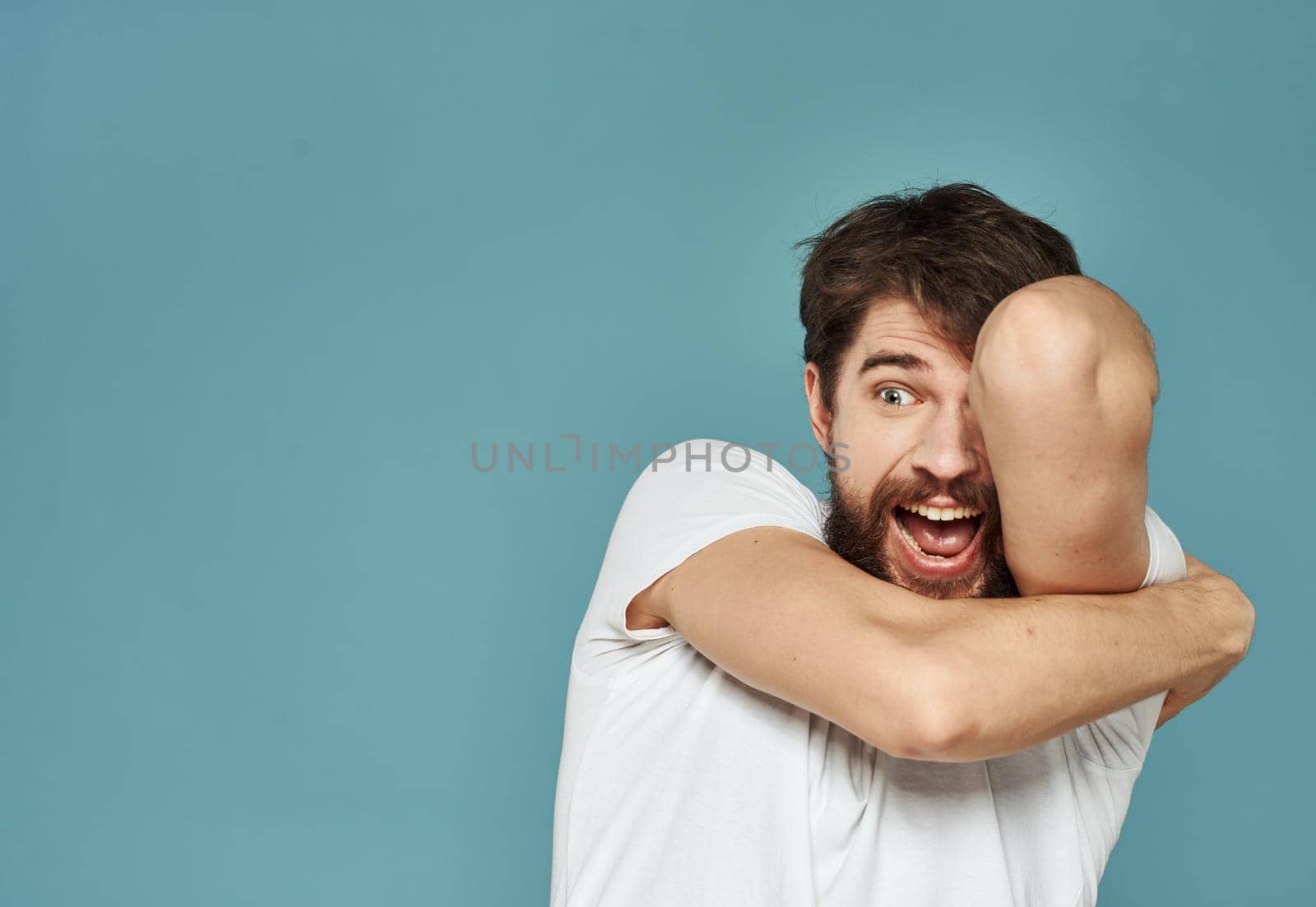 Close-up of a man gesturing with his hands on a blue background cropped view. High quality photo
