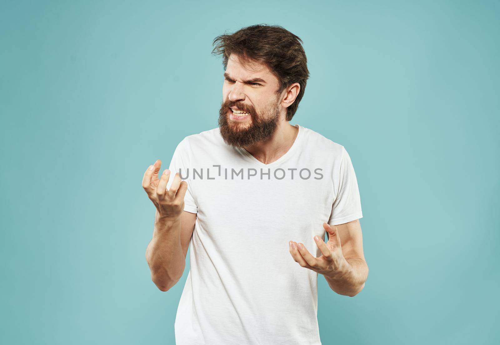 Cute man on a blue background gestures with his hands stress Scream irritability outrage. High quality photo