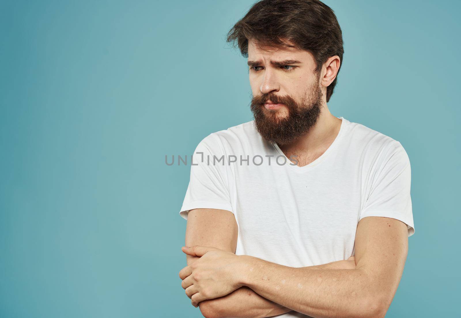 Upset man on a blue background crossed his arms on his chest emotions model sadness. High quality photo