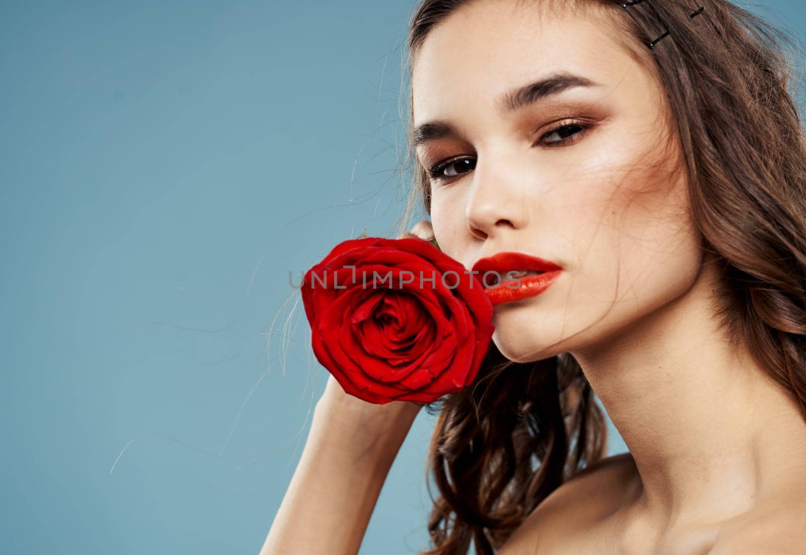 Sexy woman with bared shoulders and a red flower near the face. High quality photo