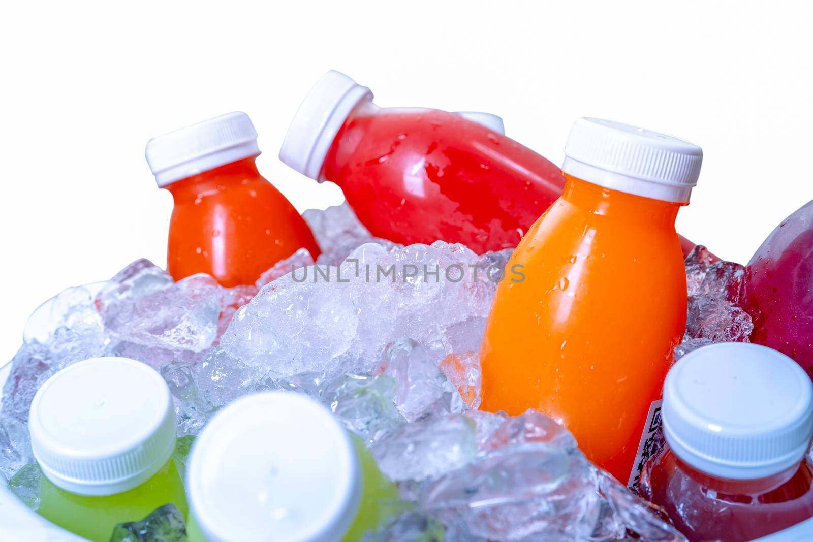 Organic cold pressed raw vegetable and fruit juice bottle in crushed ice bucket on white background. Healthy drink. Trendy juice beverage. Detox juice from fresh fruits and vegetables. Orange juice.