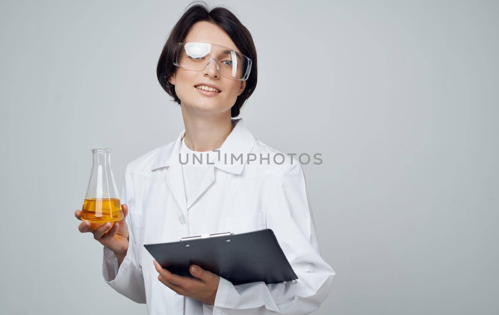 female laboratory assistant with a flask in his hands glasses on his face and a medical gown. High quality photo
