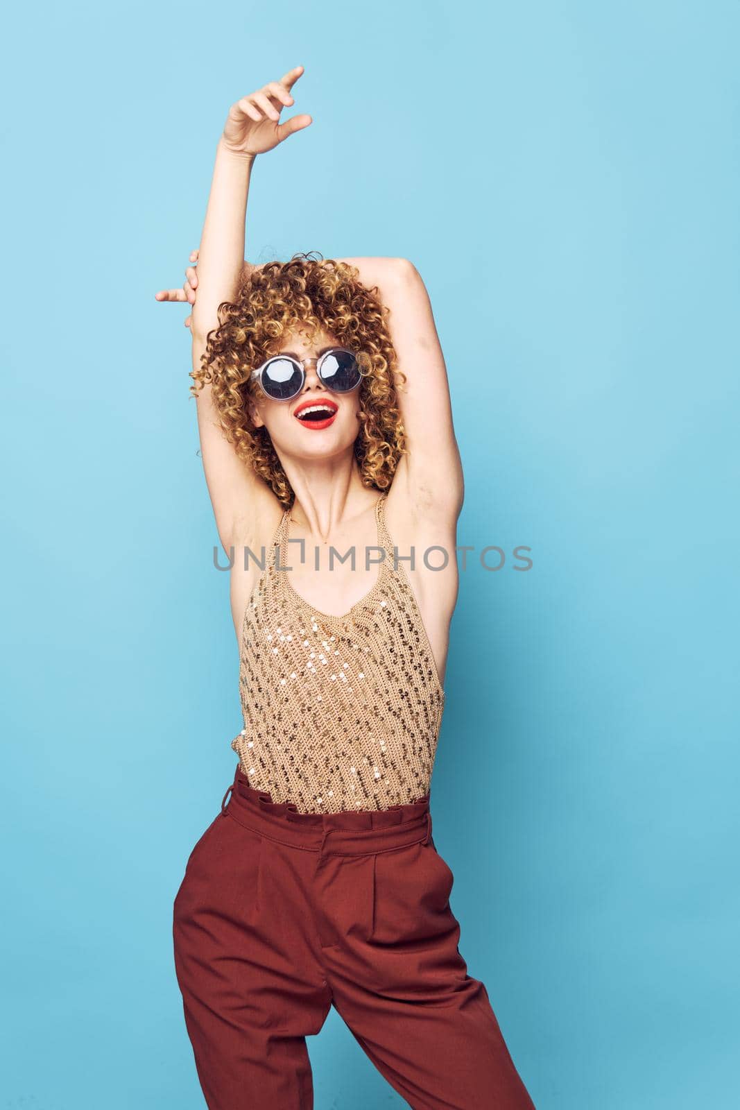 Lady curly hair blue background red lips model brown pants by SHOTPRIME