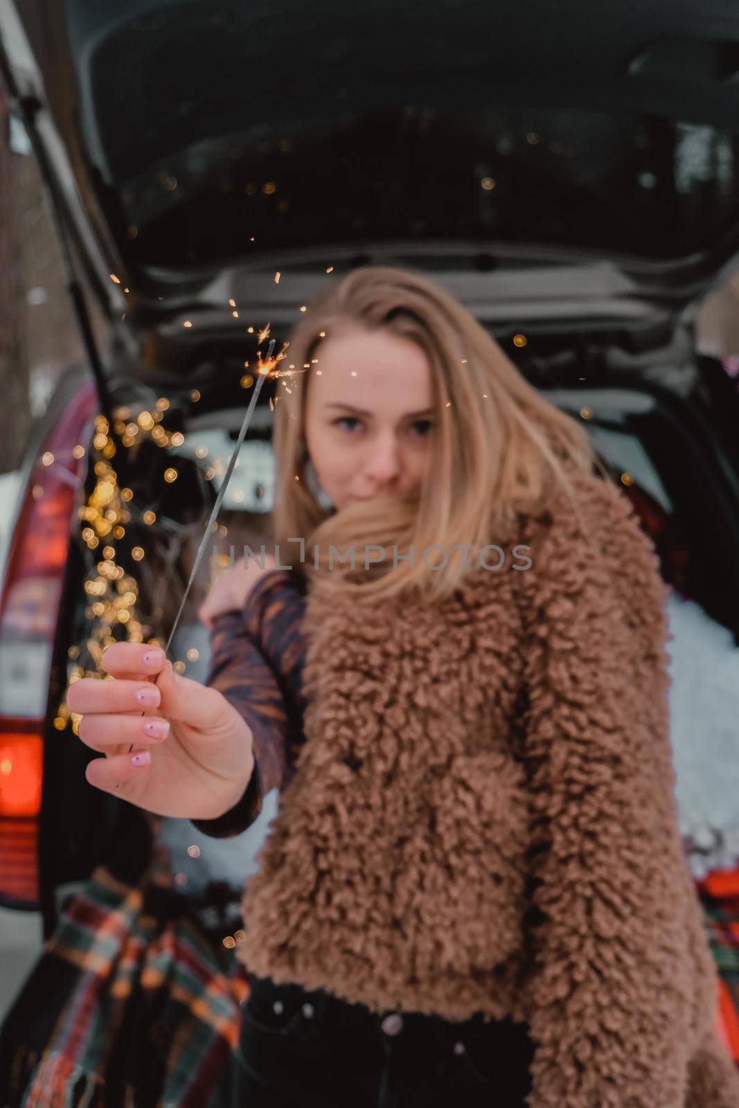 Attractive beautiful young woman in sweater staying next to the car in forest. Winter vacation. Holidays. Smilling by anna_stasiia