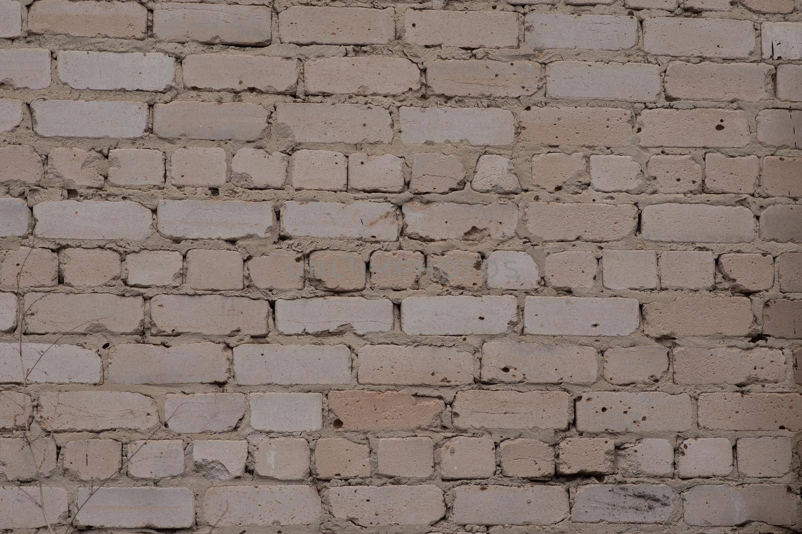 A brick white wall. The wall is poorly laid. Texture