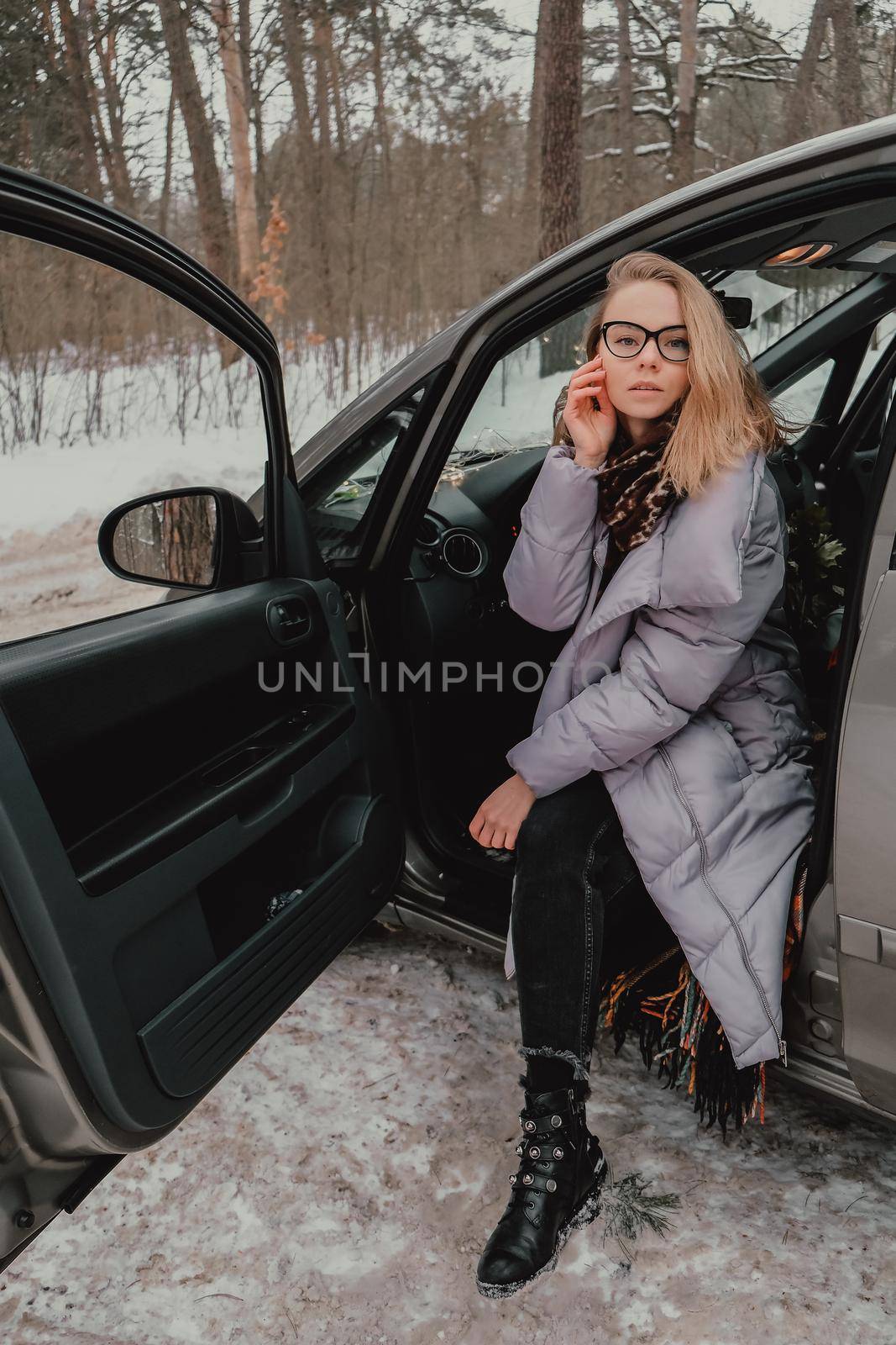 Attractive young female looks out the car window waiting for a trip and smile. Winter travel. Woman sitting in the car by anna_stasiia