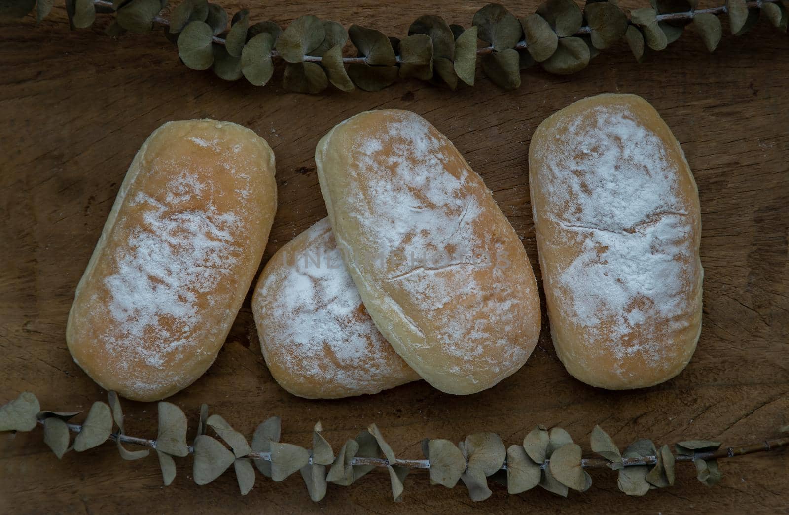 Three homemade sweet cream soft buns and sprinkled with icing sugar on old rustic wooden table. Bakery and dessert concept, Selective focus.