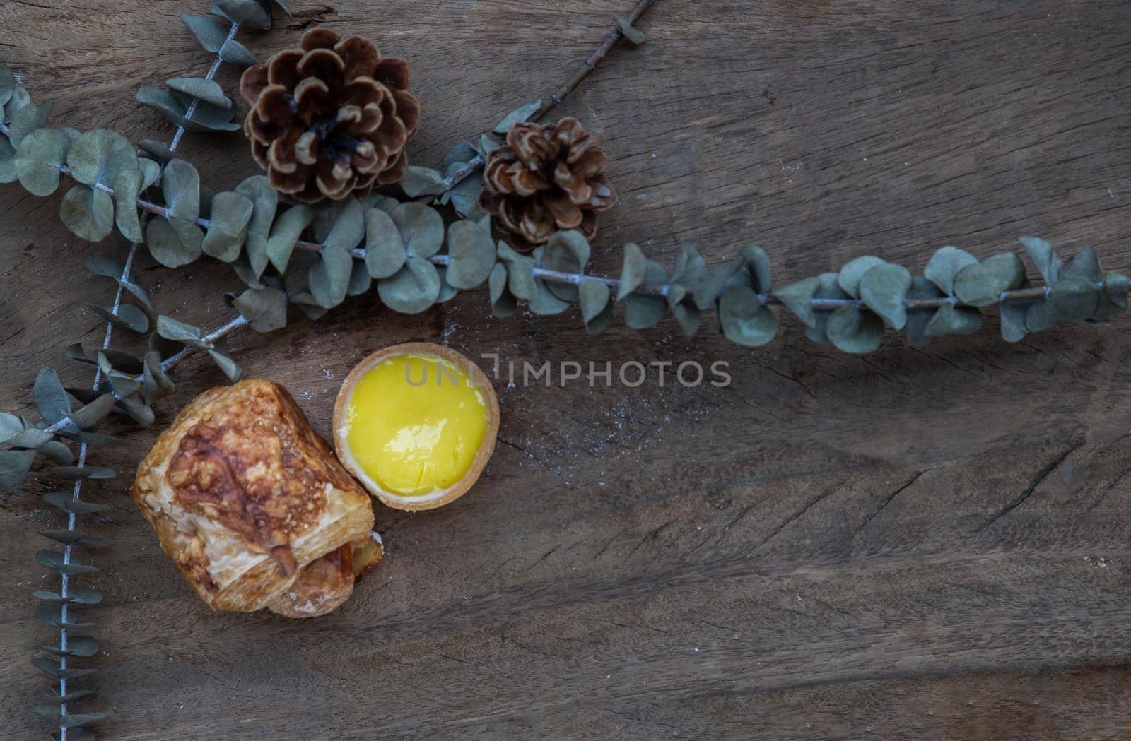 Baked croissant sausage and Lemon tart with Dried flowers on old rustic wooden table. Bakery and dessert concept, Selective focus.