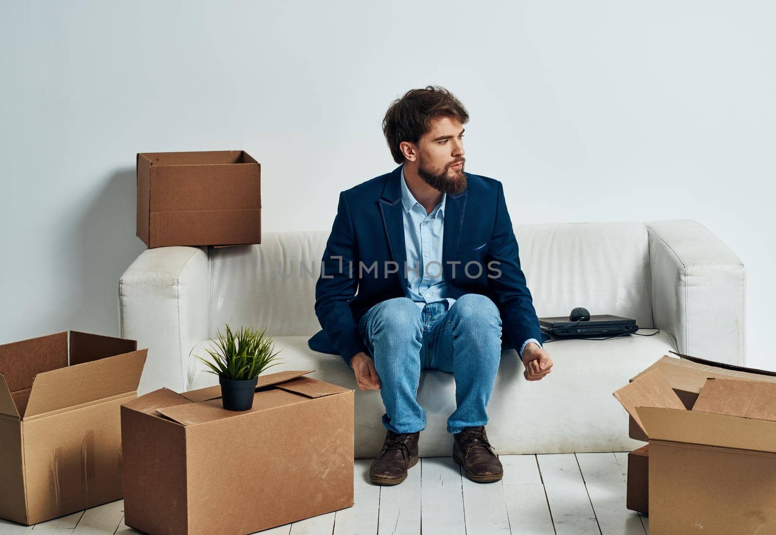 Business man sits on the couch near laptop boxes with packing things Professional by SHOTPRIME