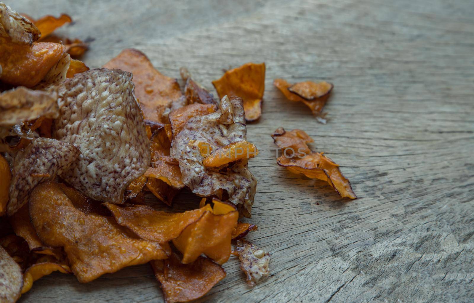 Mixed thai sweets made from sliced sweet potato coated with sugar (Potato chip) on rustic wooden background. Copy space, Selective focus.