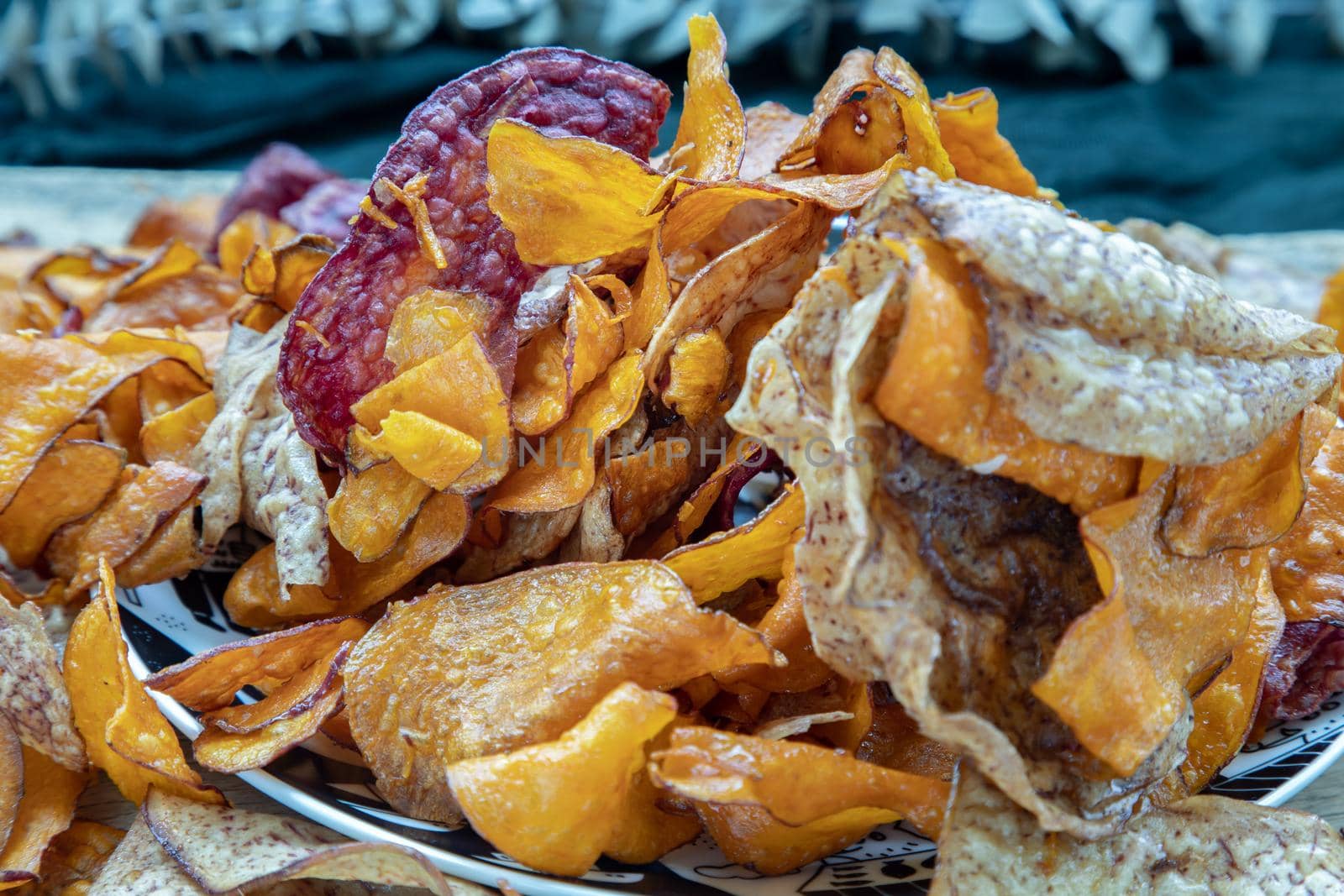 Mixed thai sweets made from sliced sweet potato coated with sugar (Potato chip) on ceramic plate over rustic wooden background. Selective focus.