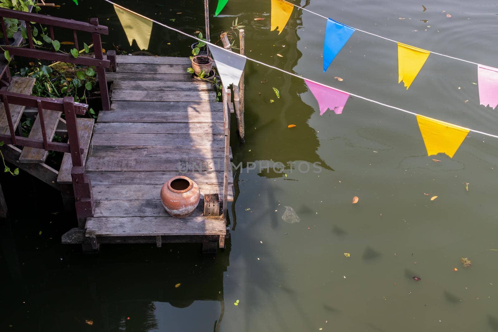 Old big earthen jar or Vintage clay jar for water storage on pier waterfront balcony pavilion at thai ancient style house.  Selective focus.