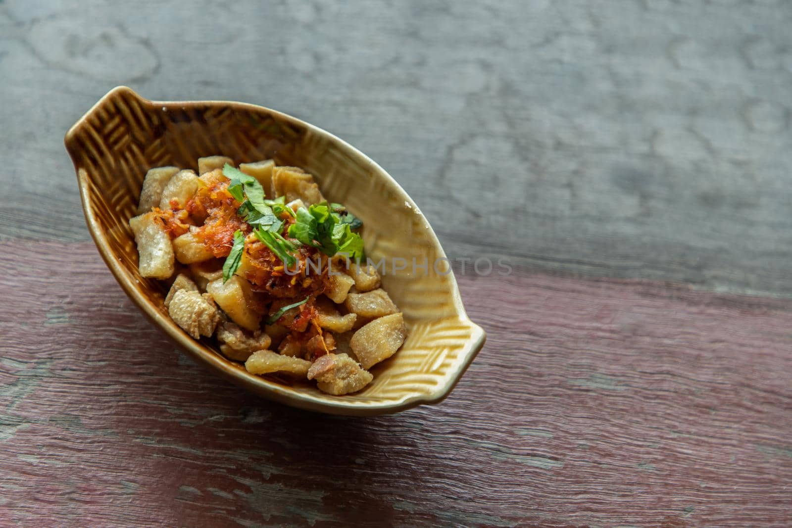 Pork Crackling from lard or Stir-Fried Pork Crackle seasoning with spicy-sweet dipping sauce in ceramic bowl. It is a delicious appetizer. Copy space, Selective focus.