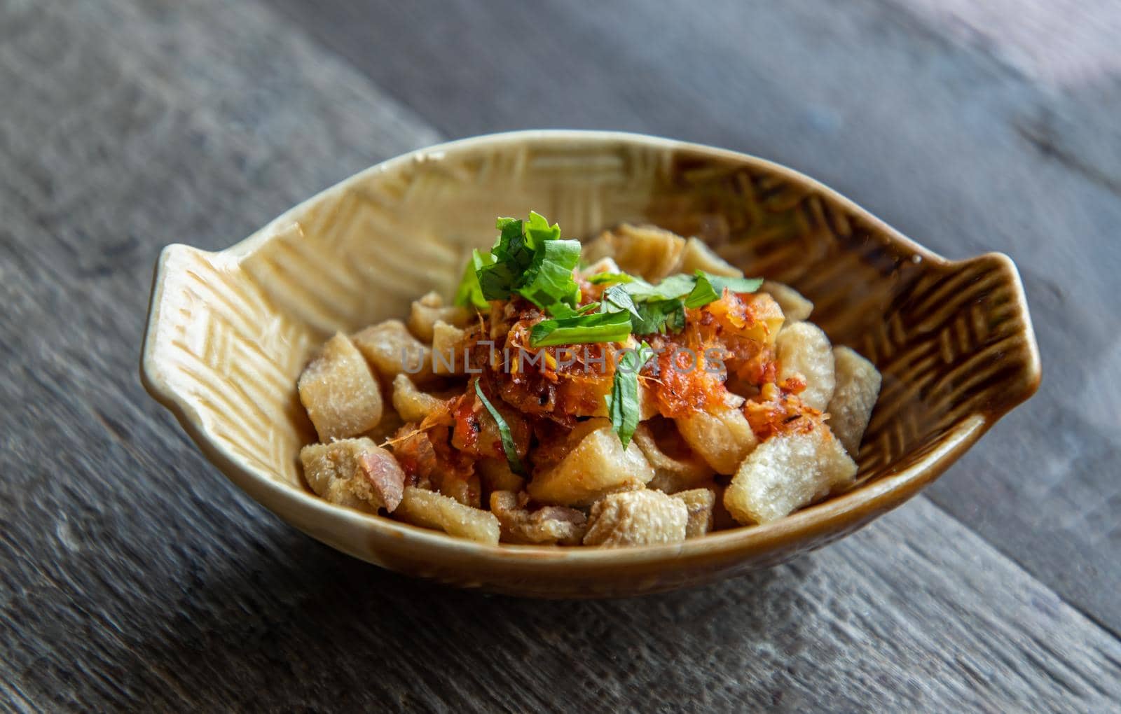Pork Crackling from lard or Stir-Fried Pork Crackle seasoning with spicy-sweet dipping sauce in ceramic bowl. It is a delicious appetizer. Selective focus.