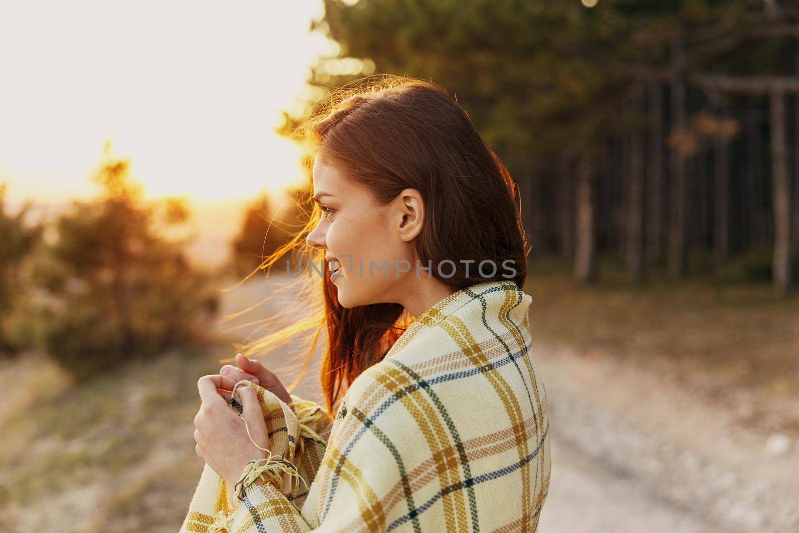 Joyful traveler on a path in the forest with a plaid blanket on her shoulders by SHOTPRIME