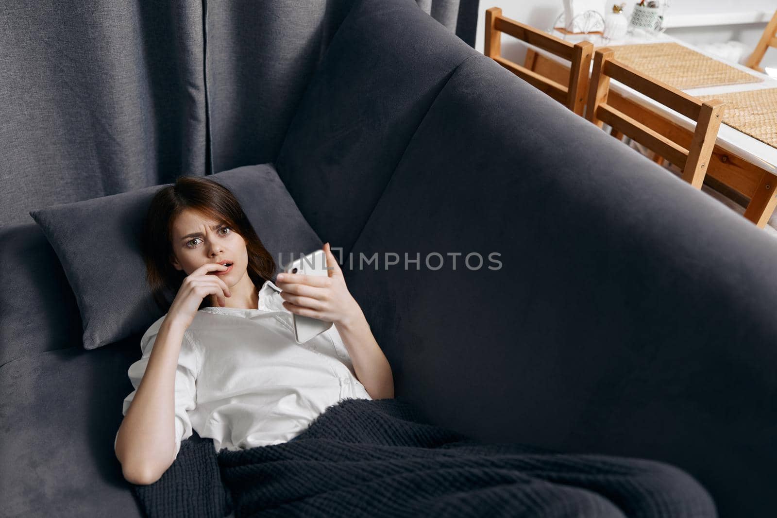 woman indoors lies on the couch with a mobile phone in her hand top view. High quality photo