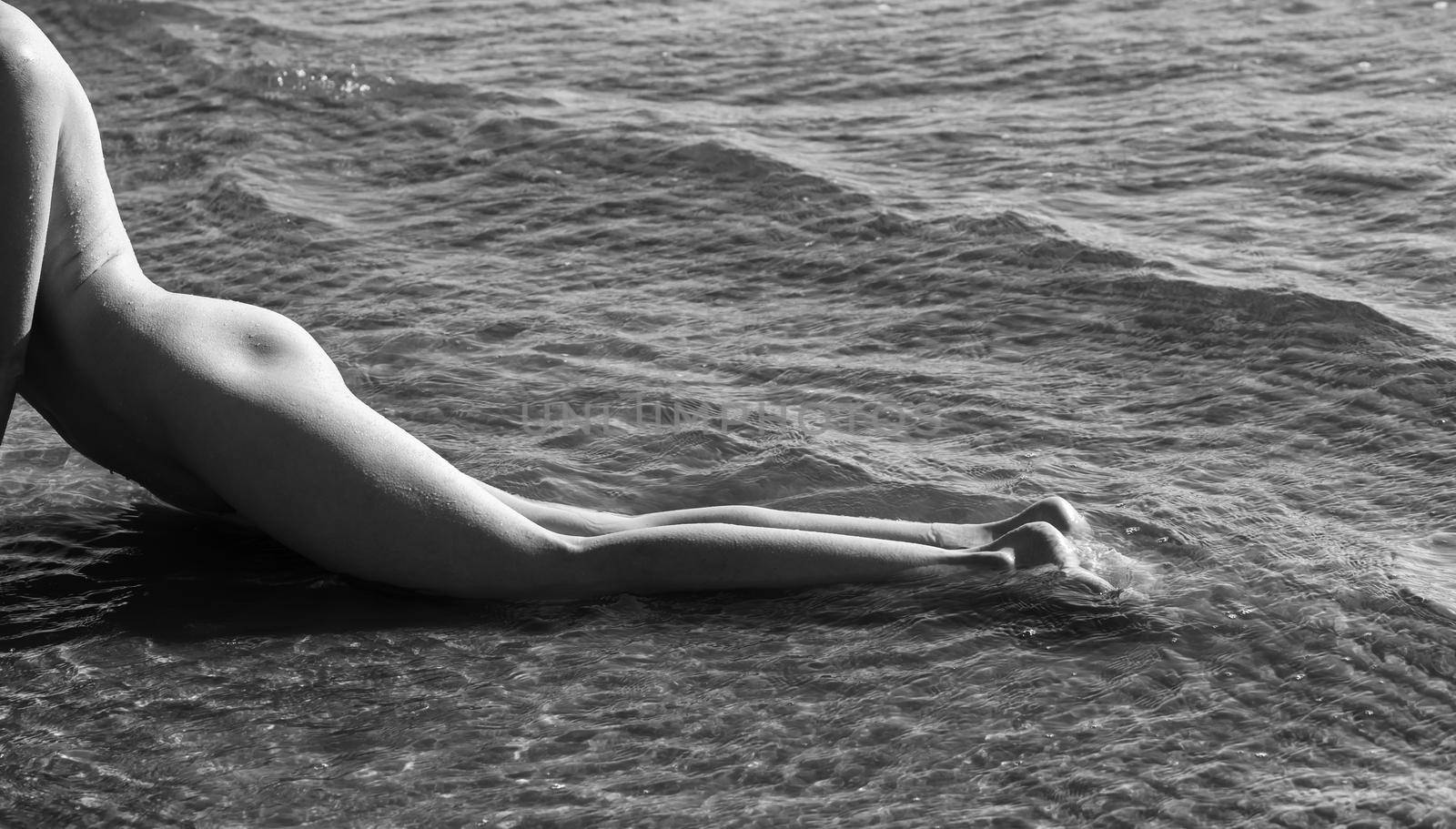 Beautiful girl outdoors enjoying nature. Young naked woman enjoys the sea on the coast. View from the back
