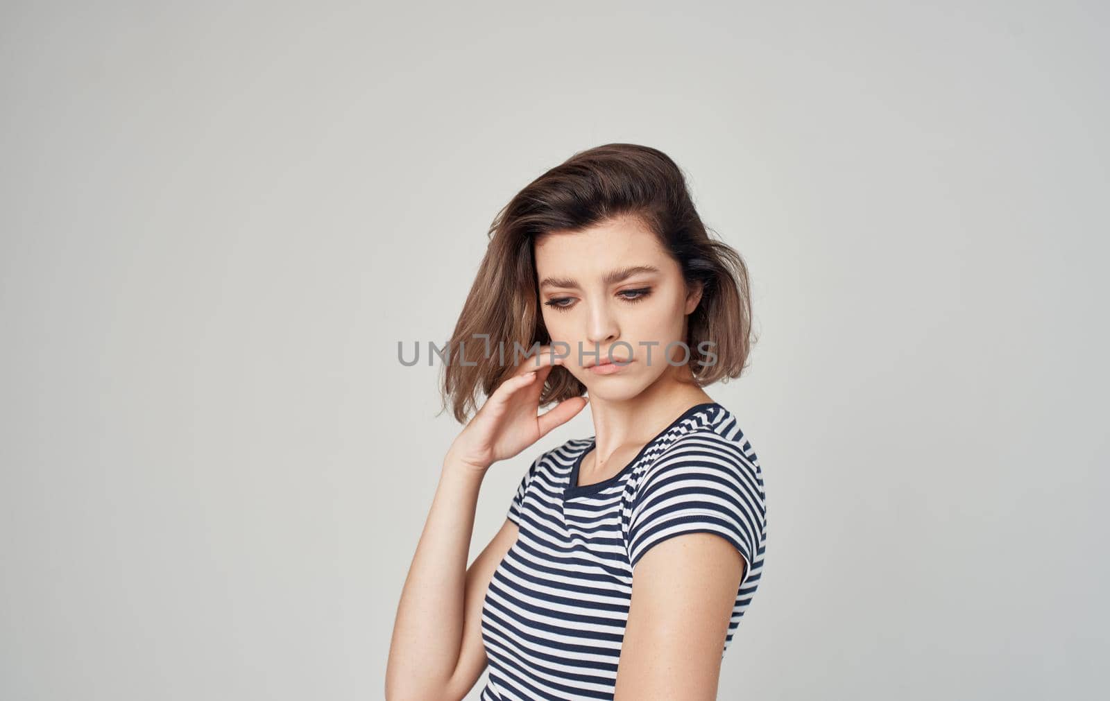 pretty model woman in striped t-shirt gesturing with hands on gray background Copy Space. High quality photo