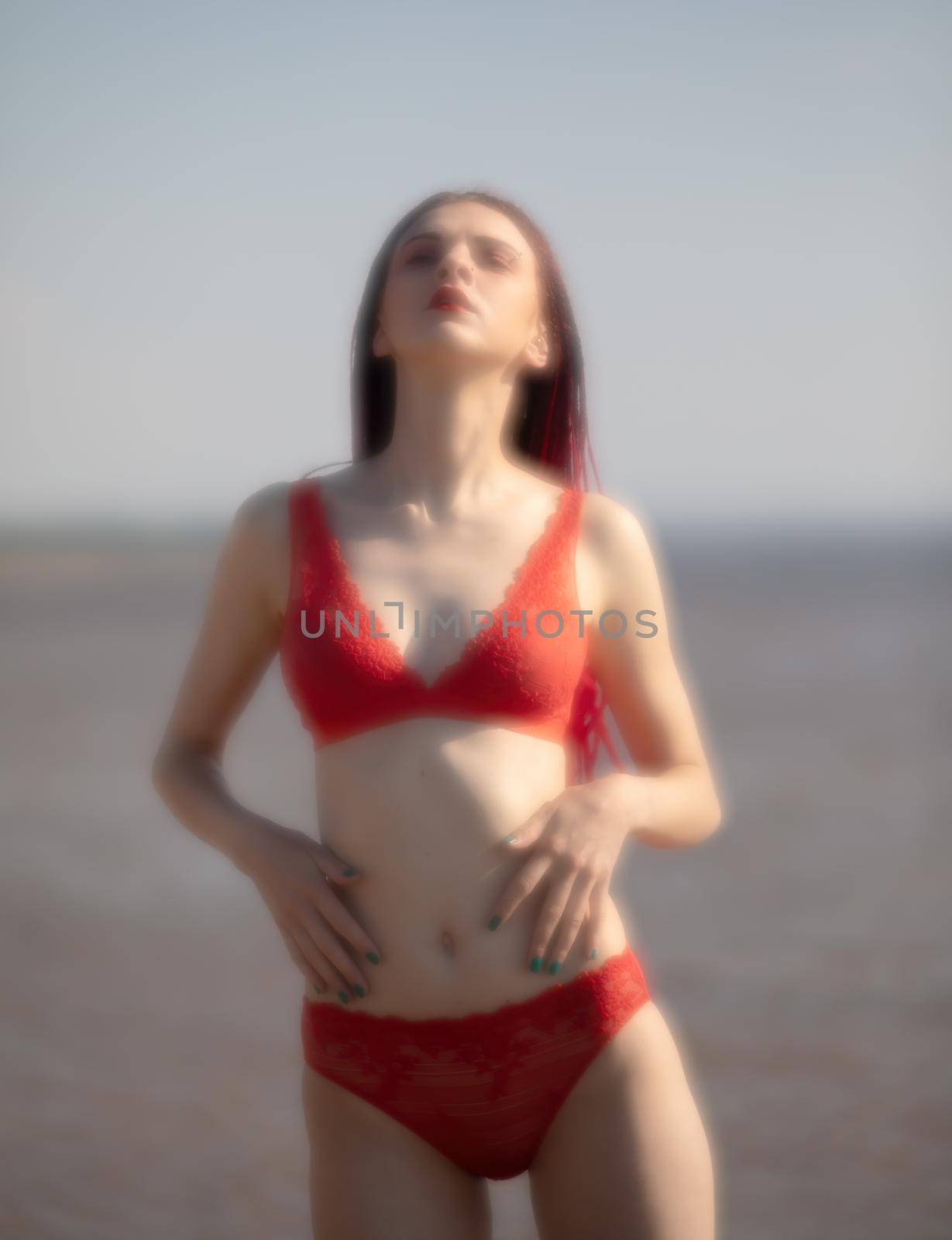 Soft focus blurred image of a beautiful young woman with scarlet dreadlocks and red bathing suit enjoying nature on the beach